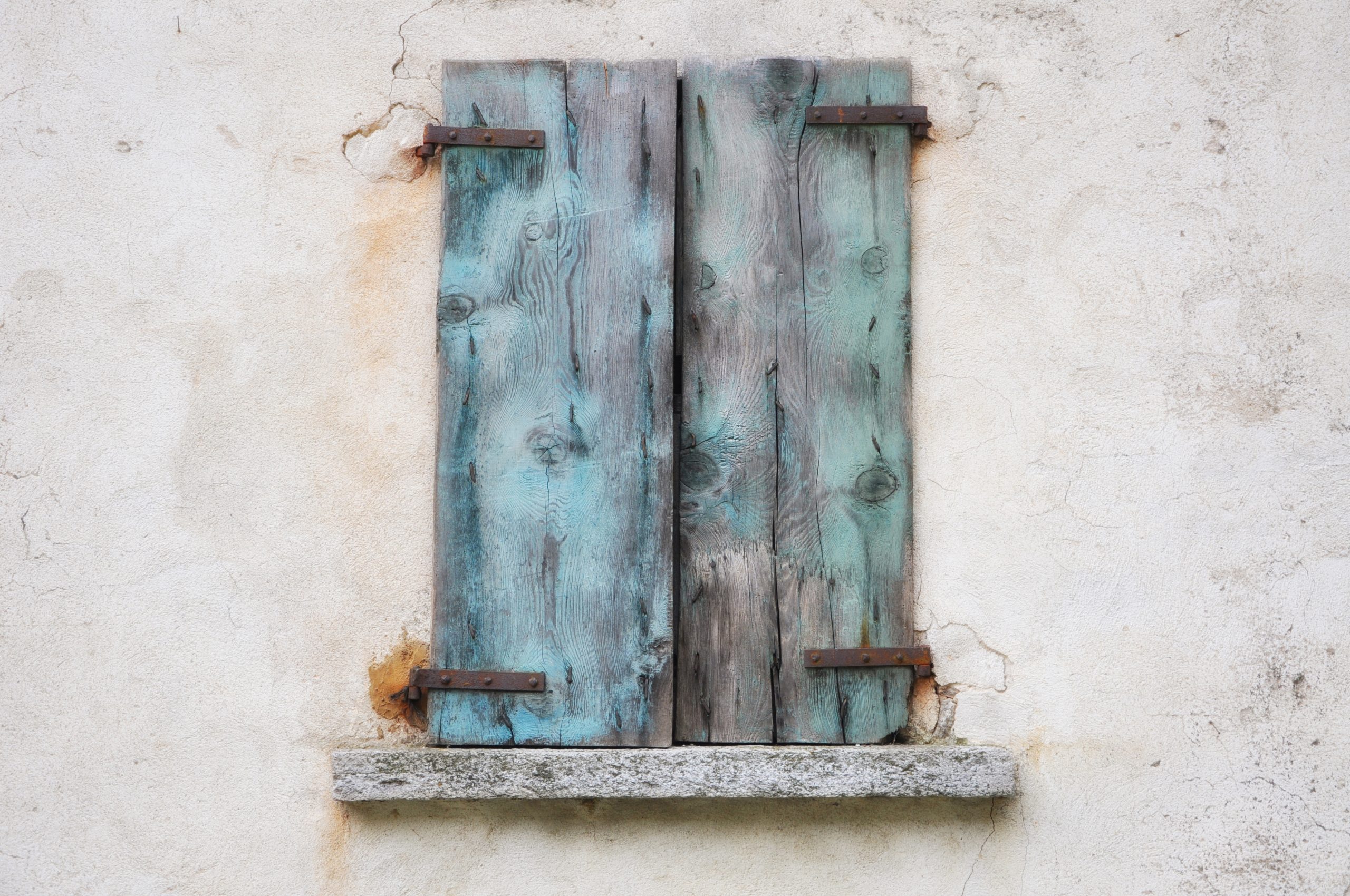 Old weathered wall with blue rusty wooden shutters